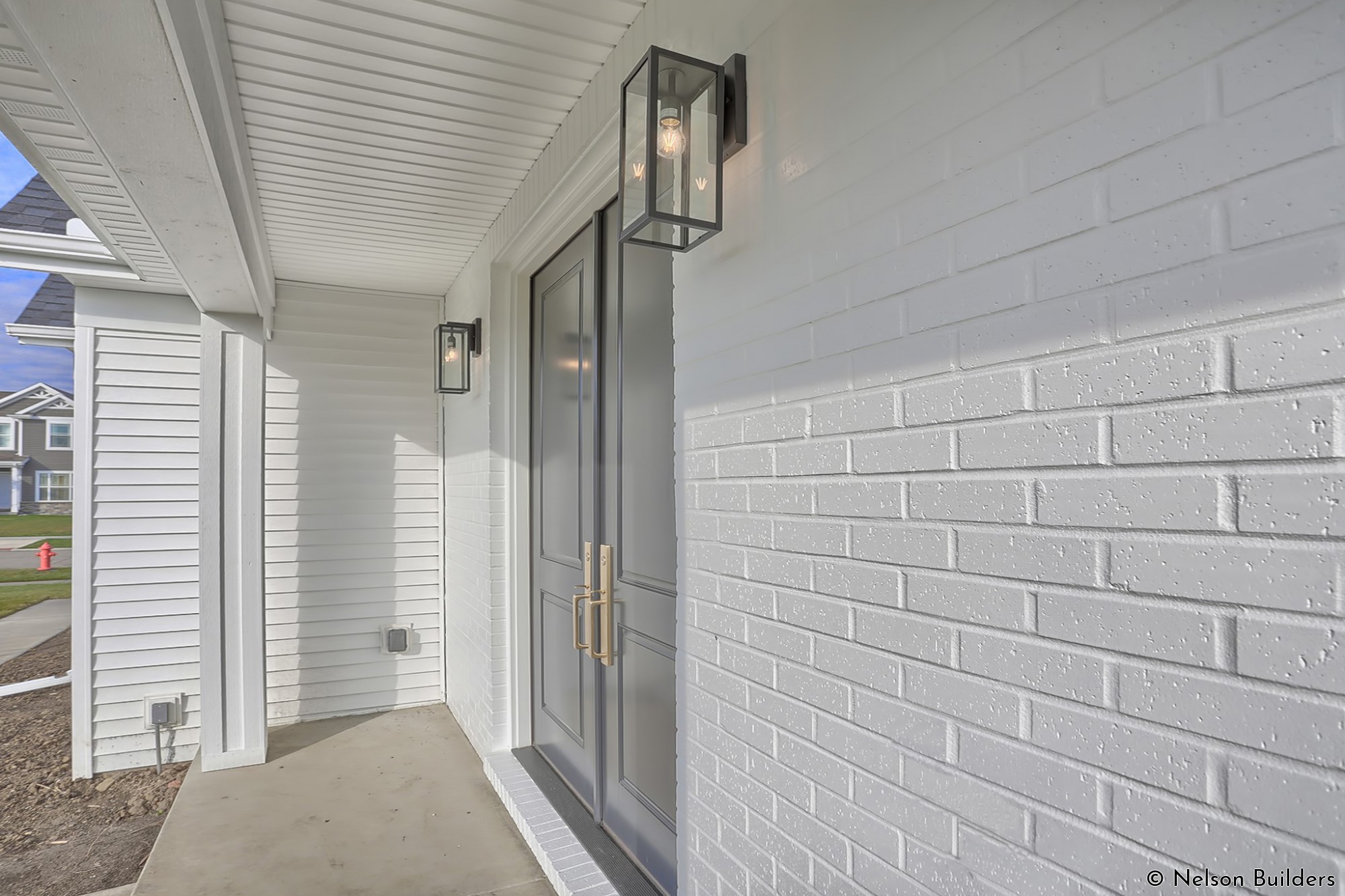 The contrast on the front porch brings elegance to the entryway, from the brass handles, to the dark colored door, to the painted brick.
