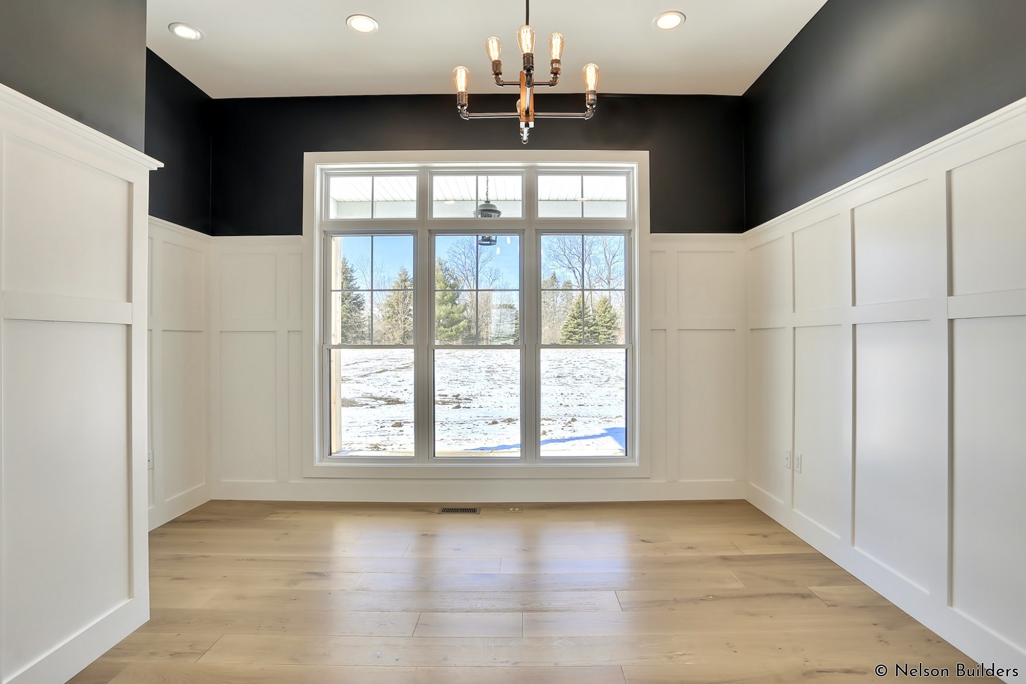 A formal office is found near the master bedroom and is adorned with paneled walls and black accents.