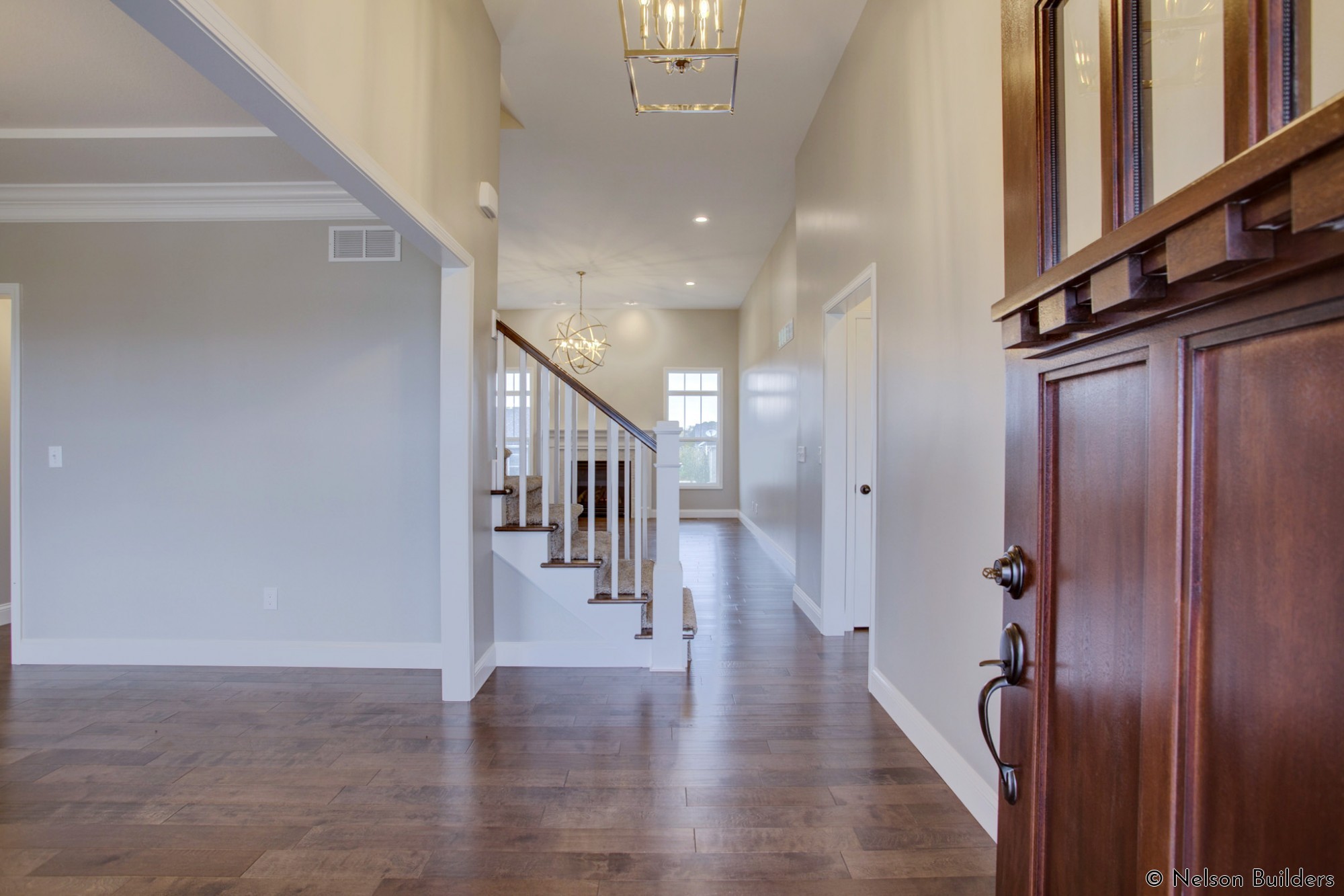 The wood front door opens into the grand foyer and great room of this new Cherrydale plan by Nelson Builders.