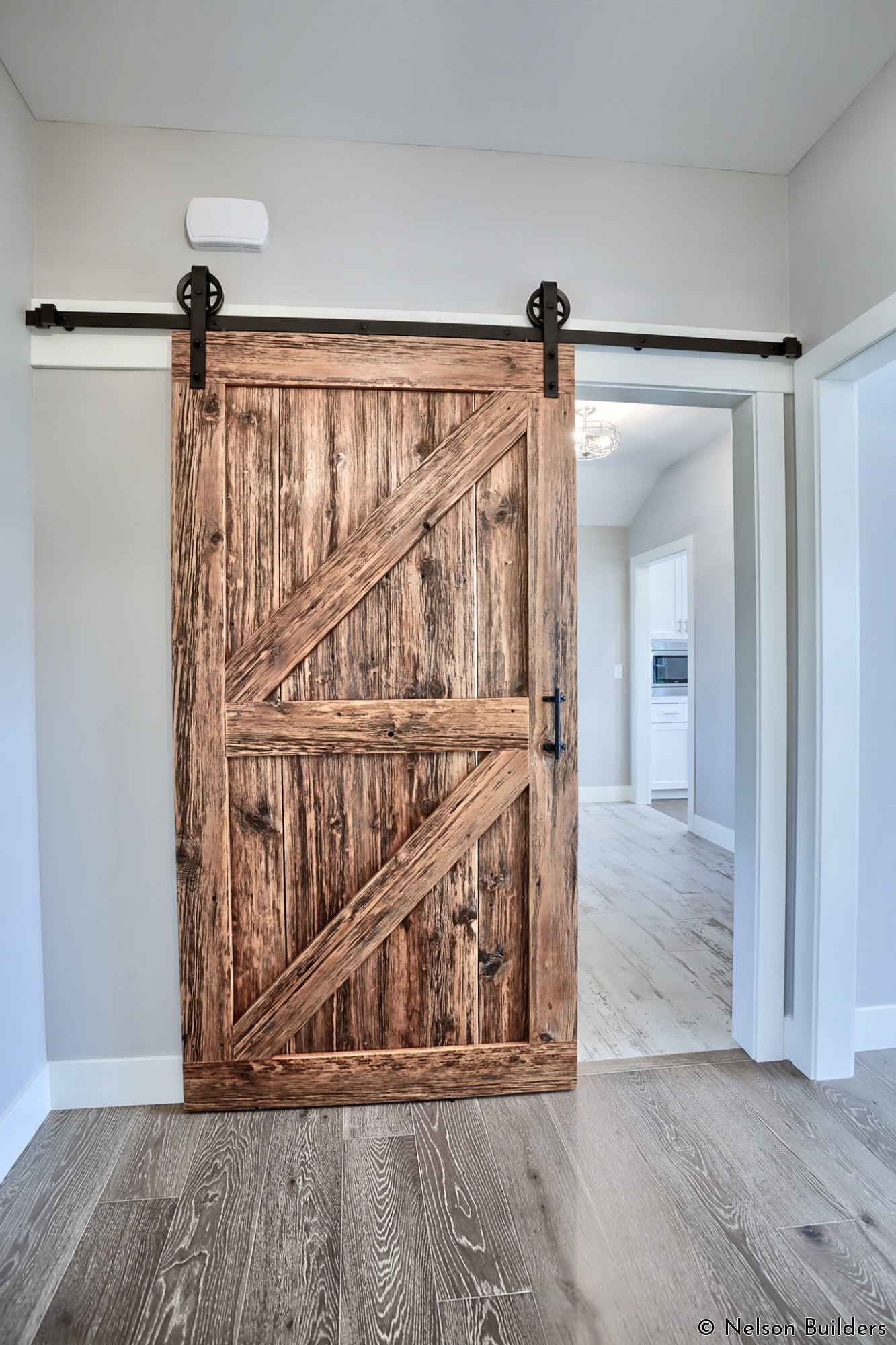The laundry room is tucked away behind this stunning barn door, finished by the owners.