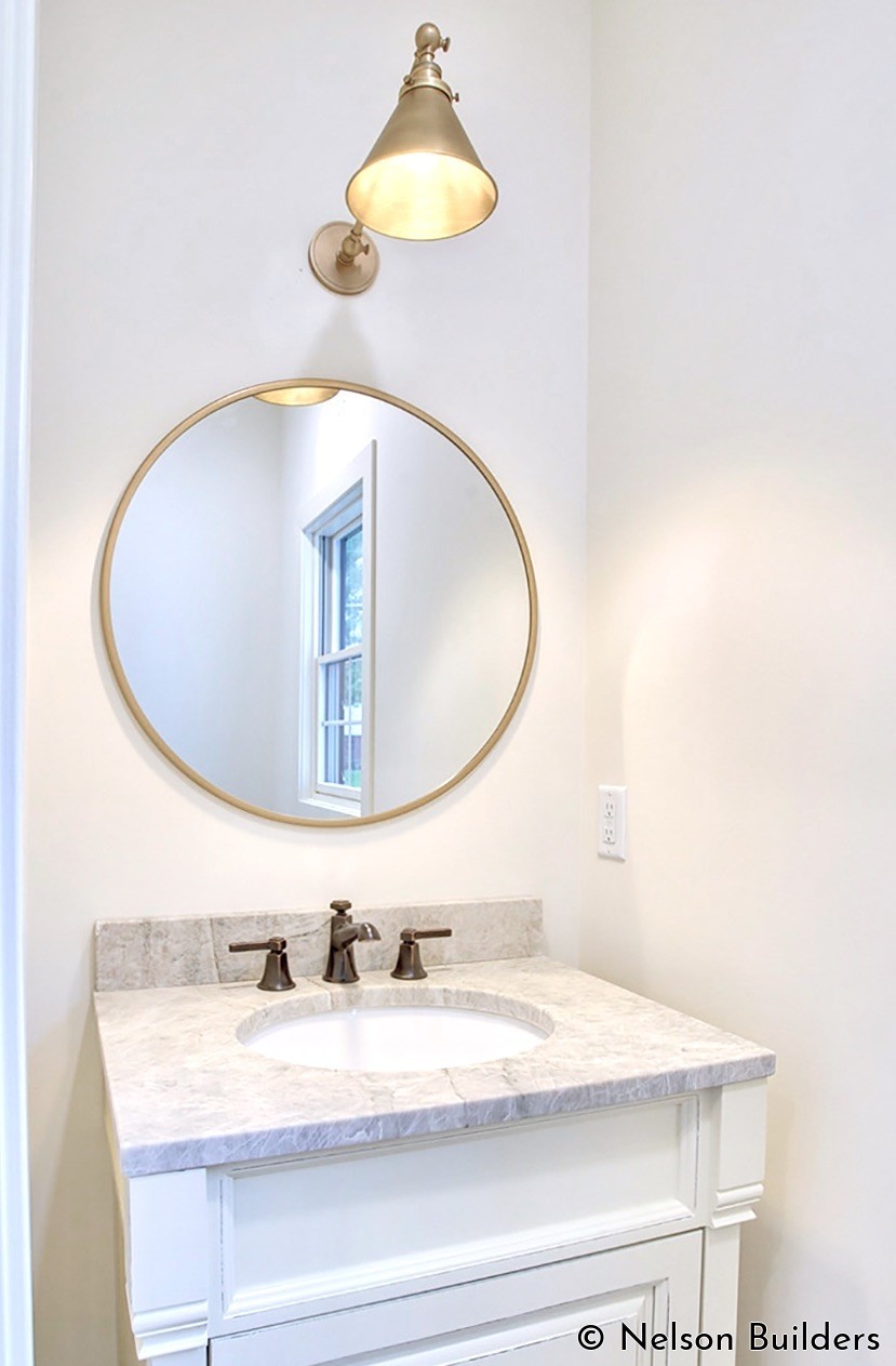 The powder bath has a more elegant feel with the furniture base vanity and champagne bronze fixtures.