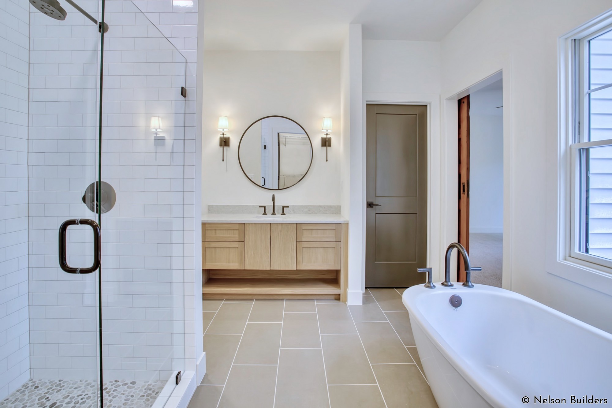 The master bath features custom white oak cabinets, a pebble-tile shower floor, and soaking tub.